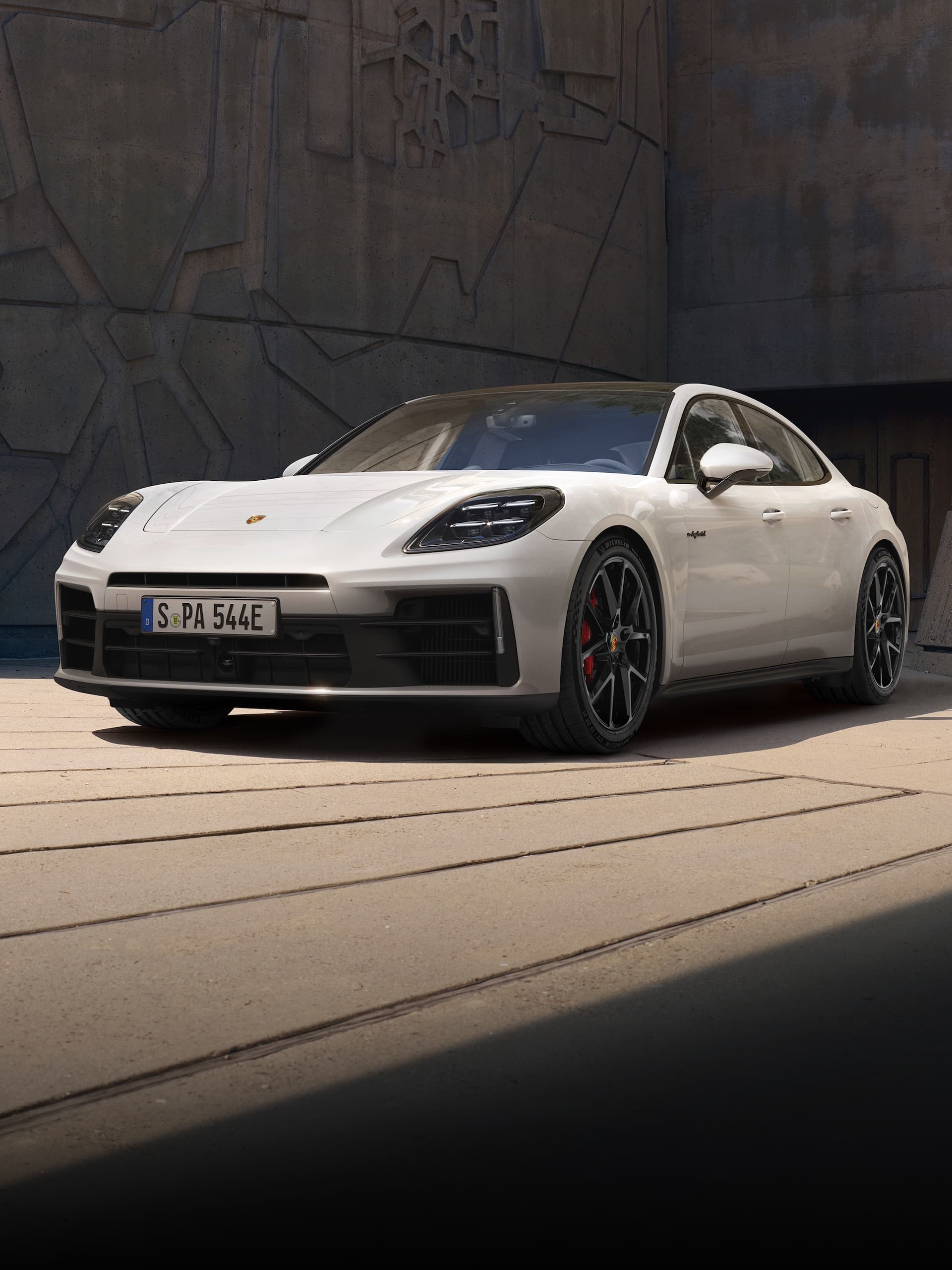Une Porsche Panamera garée devant un immeuble moderne.